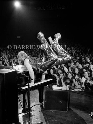 PHOTOGRAPHED BY BARRIE WENTZELL
"Bryan Forbes, the English filmmaker and neighbor of Elton, came along to this gig and filmed the performance; so at least there was good lighting and Elton was in great form. He was performing “Crocodile Rock” in this picture. I’d done Elton’s first photo shoots as a solo performer after he left Long John Baldry’s band and had a hard time getting him to loosen up..." https://www.morrisonhotelgallery.com/photographs/ZMFCle/Elton-John-Sundown-Theatre-Edmonton-North-London-1973
