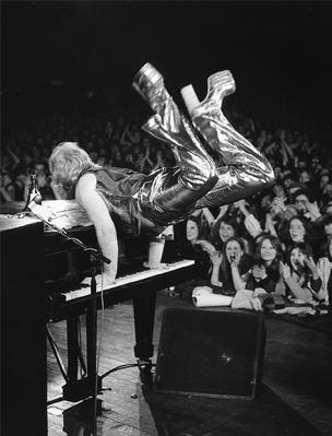 PHOTOGRAPHED BY BARRIE WENTZELL
"Bryan Forbes, the English filmmaker and neighbor of Elton, came along to this gig and filmed the performance; so at least there was good lighting and Elton was in great form. He was performing “Crocodile Rock” in this picture. I’d done Elton’s first photo shoots as a solo performer after he left Long John Baldry’s band and had a hard time getting him to loosen up..." https://www.morrisonhotelgallery.com/photographs/ZMFCle/Elton-John-Sundown-Theatre-Edmonton-North-London-1973
