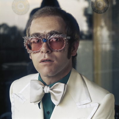 English pop singer Elton John in a white jacket and rococco spectacles, circa 1978.
