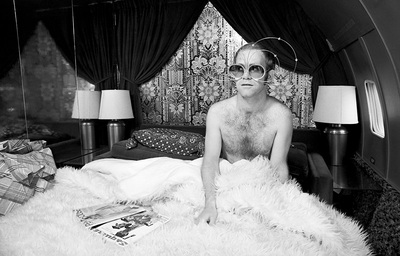 English singer and songwriter Elton John sits on a bed inside his private jet en route to Tucson, Arizona, 1974.
