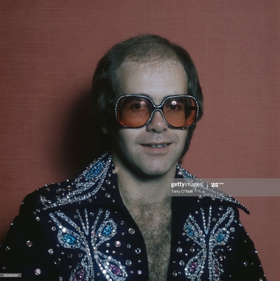 English pop singer Elton John in a rhinestone jacket and matching glasses, circa 1975.
