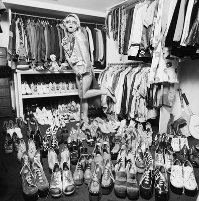 Elton John at home in London, 1975, with part of his wardrobe, notably a large collection of platform shoes.
“That’s a great one. When I was at his home, I suggested we just walk around and I’ll take some photos of him with some of his collections. I was thinking at the time, he’ll show me some sculptures or paintings. Little did I know what I was getting myself into!” – Terry O’Neill
