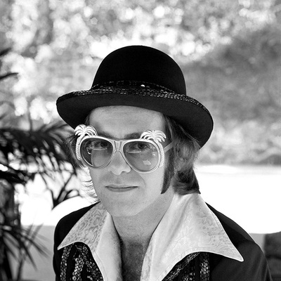 English pop singer Elton John poses for a portrait in a fur coat, hat and glasses, circa 1975.
