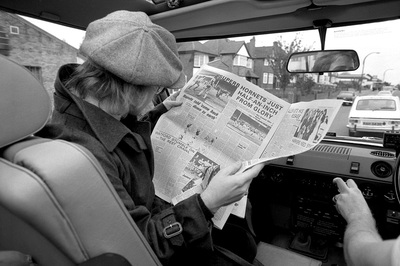 British pop singer, songwriter and musician Elton John reads a newspaper article about Watford FC, mid 1970s.
