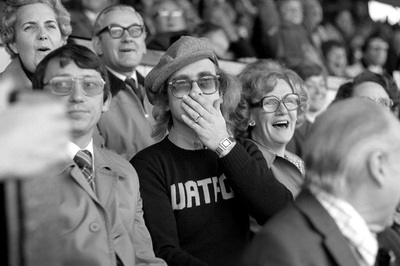 Watford FC manager Graham Taylor and pop singer Elton John cheer and spectate during a football match, late 1980s.
