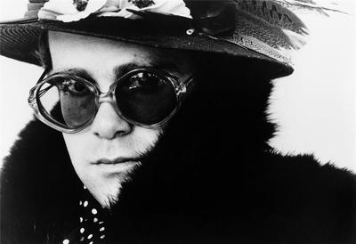 English pop singer Elton John poses for a portrait in a fur coat, hat and glasses, circa 1975.
