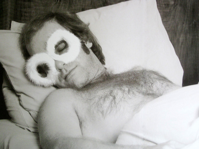 English singer and songwriter Elton John sleeps in the bed of his airplane, 1975.
