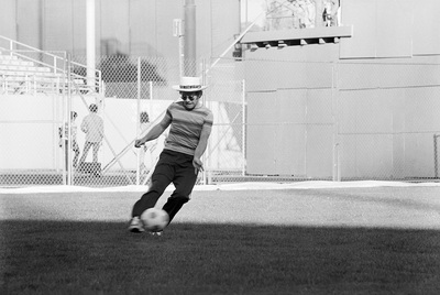 PHOTOGRAPHED BY TERRY O'NEILL
English singer songwriter Elton John playing football before his performance at Dodger Stadium in Los Angeles, 1975.
