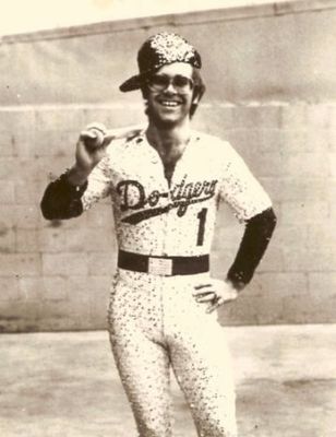 PHOTOGRAPHED BY TERRY O'NEILL
English singer and songwriter Elton John poses in Bob Mackie’s now famous sequined white Dodgers uniform at Dodger Stadium in Los Angeles, October 1975.
