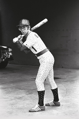 PHOTOGRAPHED BY TERRY O'NEILL
English singer and songwriter Elton John poses in Bob Mackie’s now famous sequined white Dodgers uniform at Dodger Stadium in Los Angeles, October 1975.
