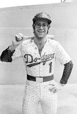 PHOTOGRAPHED BY TERRY O'NEILL
English singer and songwriter Elton John poses in Bob Mackie’s now famous sequined white Dodgers uniform at Dodger Stadium in Los Angeles, October 1975.
