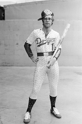 PHOTOGRAPHED BY TERRY O'NEILL
English singer and songwriter Elton John poses in Bob Mackie’s now famous sequined white Dodgers uniform at Dodger Stadium in Los Angeles, October 1975.
