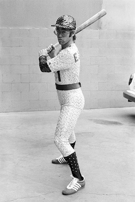 PHOTOGRAPHED BY TERRY O'NEILL
English singer and songwriter Elton John poses in Bob Mackie’s now famous sequined white Dodgers uniform at Dodger Stadium in Los Angeles, October 1975.
