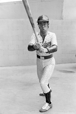 PHOTOGRAPHED BY TERRY O'NEILL
English singer and songwriter Elton John poses in Bob Mackie’s now famous sequined white Dodgers uniform at Dodger Stadium in Los Angeles, October 1975.
