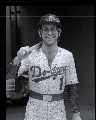 PHOTOGRAPHED BY TERRY O'NEILL
English singer and songwriter Elton John poses in Bob Mackie’s now famous sequined white Dodgers uniform at Dodger Stadium in Los Angeles, October 1975.
