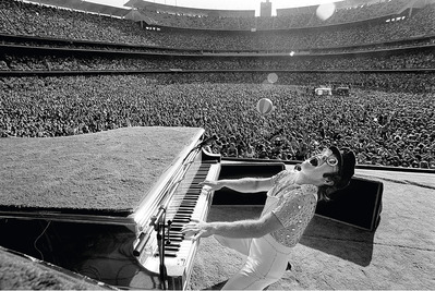 PHOTOGRAPHED BY TERRY O'NEILL
"This iconic image of Elton John was taken at a period where he was littering the rock landscape with hit after hit en route to delivering a couple No. 1 albums per year. His concerts, complete with outrageous costumes and stage antics, were legendary. On the second day, of the sold-out back-to-back concerts, Elton introduced Terry O'Neill to the audience by saying..." https://www.morrisonhotelgallery.com/photographs/nWEa7K/Elton-John-Dodger-Stadium-Los-Angeles-CA-1975
