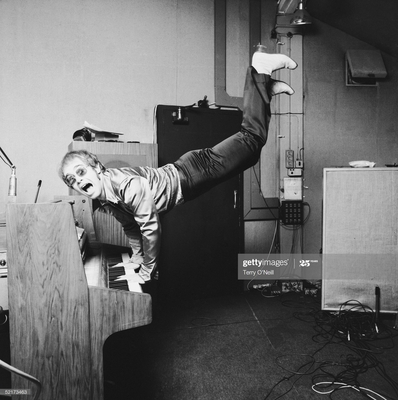 Musician and singer Elton John performing a handstand on his piano, London 1972.
