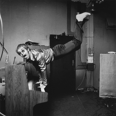 Musician and singer Elton John performing a handstand on his piano, London 1972.
